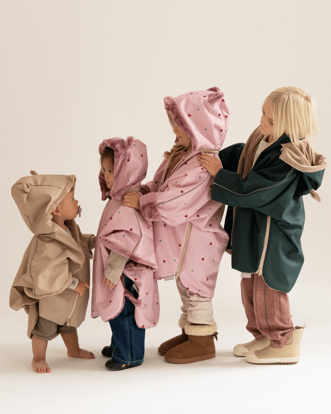 Dzieci stojące razem ubrane w wodoodporne poncza samochodowe w kolorach pastelowych
